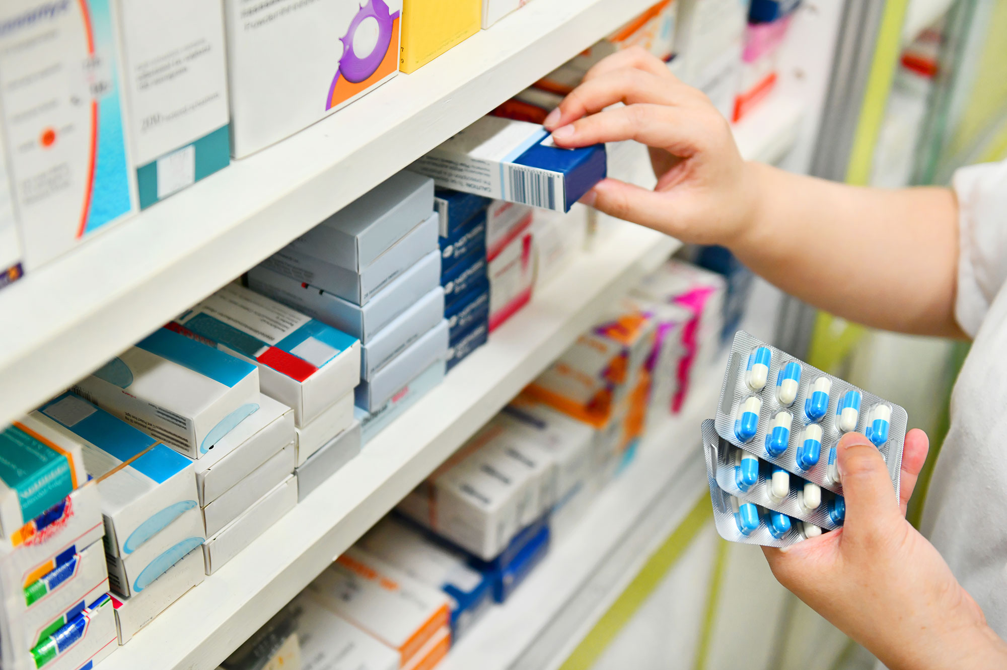 A pharmacist stacking a shelf.